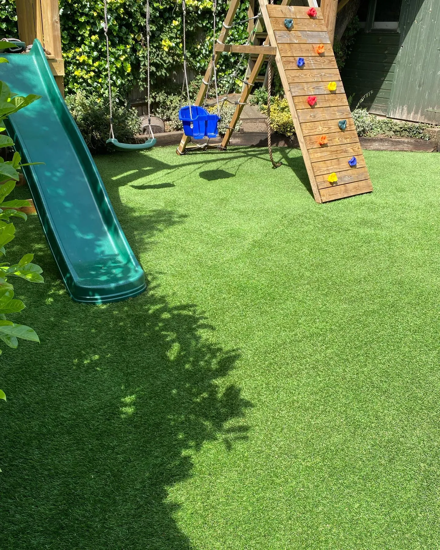 Children’s play area with slide and swings set on artificial grass
