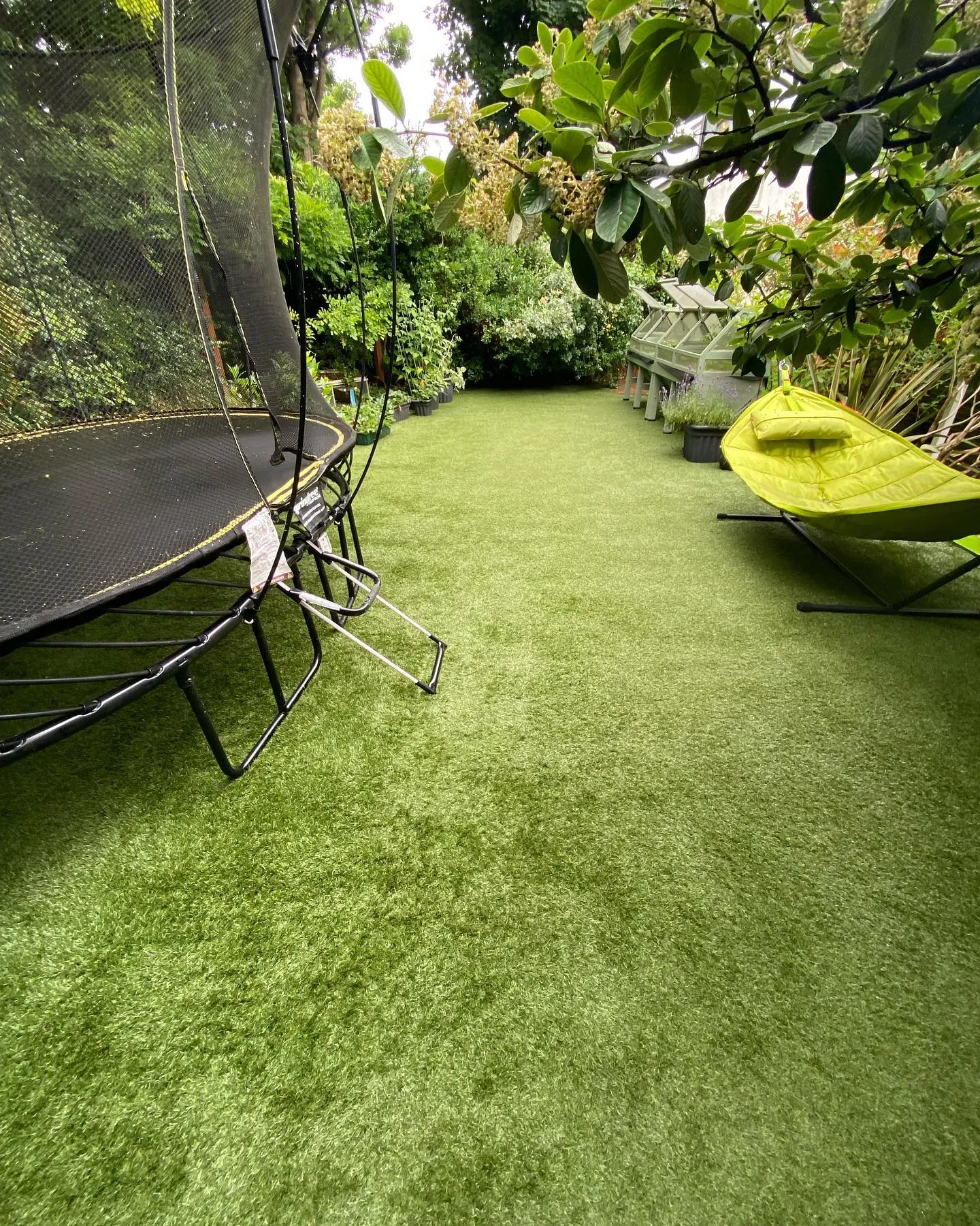 Back garden with artificial grass, trampoline and seating area
