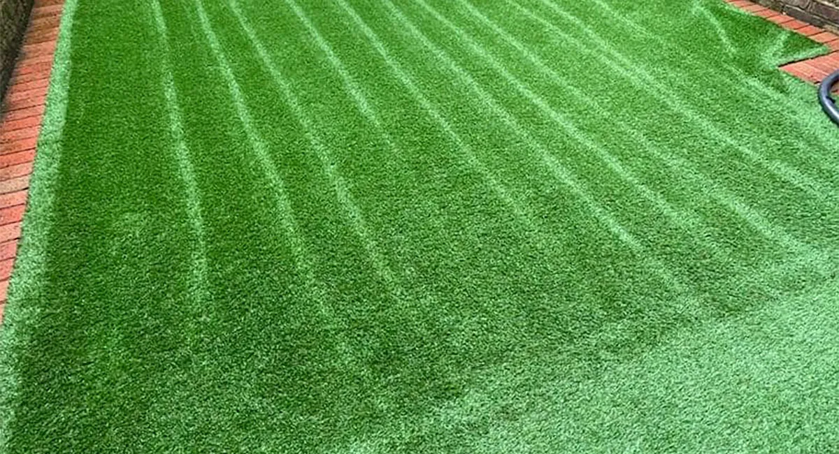 Close-up of a striped artificial lawn between brick edging